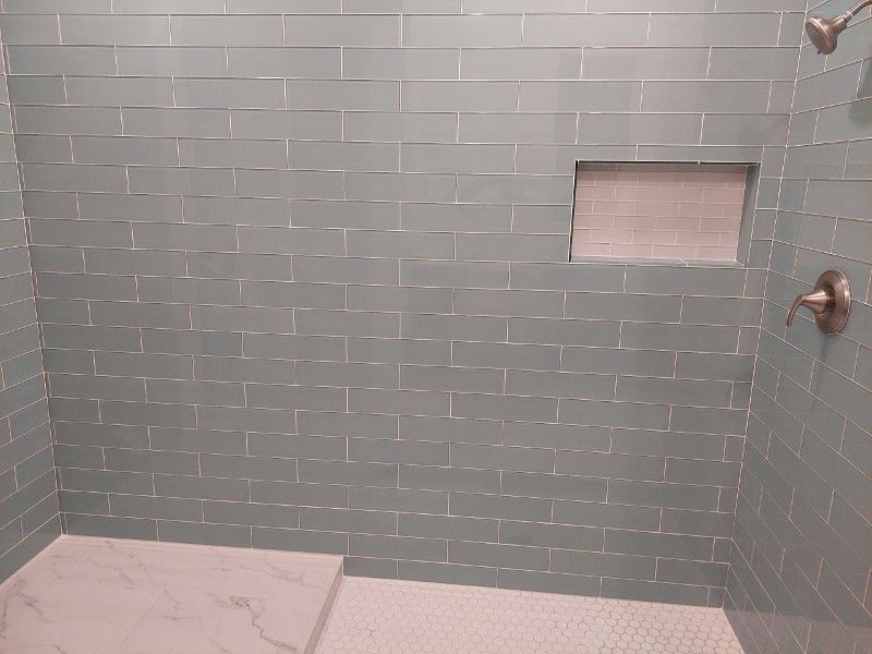 A bathroom with a walk in shower and a brick wall.