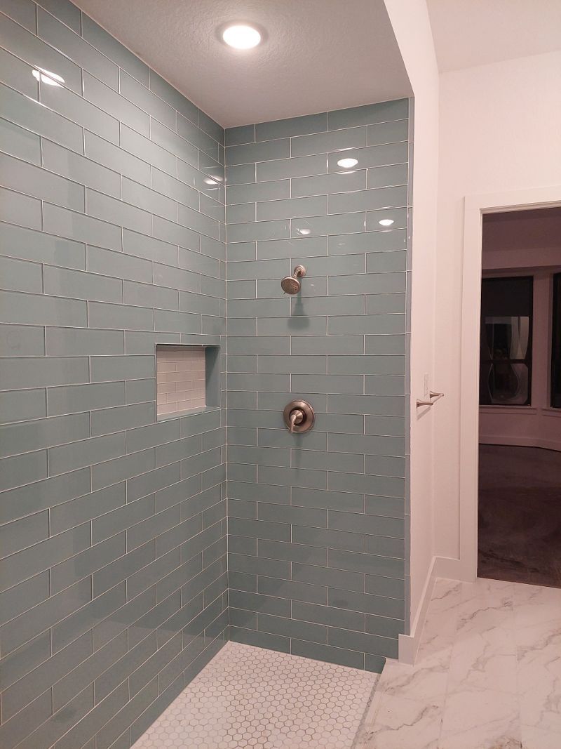 A bathroom with blue tiles and a walk in shower.