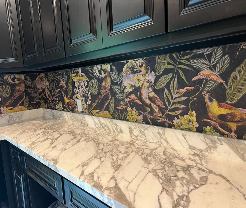 A kitchen with a marble counter top and black cabinets.