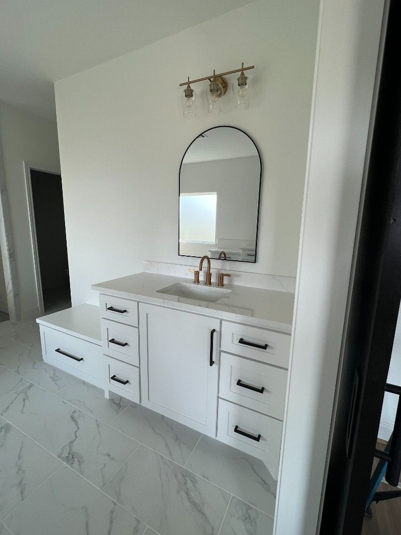 A bathroom with a sink , mirror and drawers.