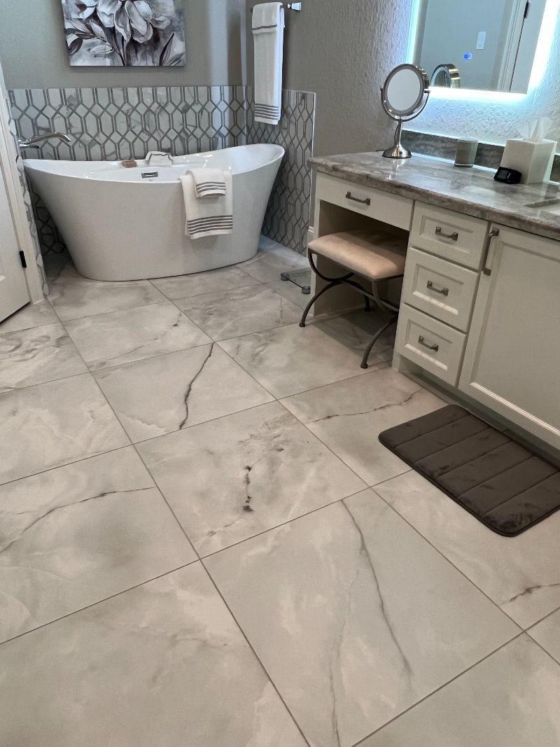 A bathroom with a bathtub , sink , mirror and marble floor.
