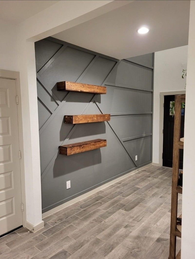 A hallway with a gray wall and wooden shelves on it.