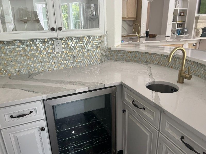 A kitchen with white cabinets , a sink , and a wine cooler.