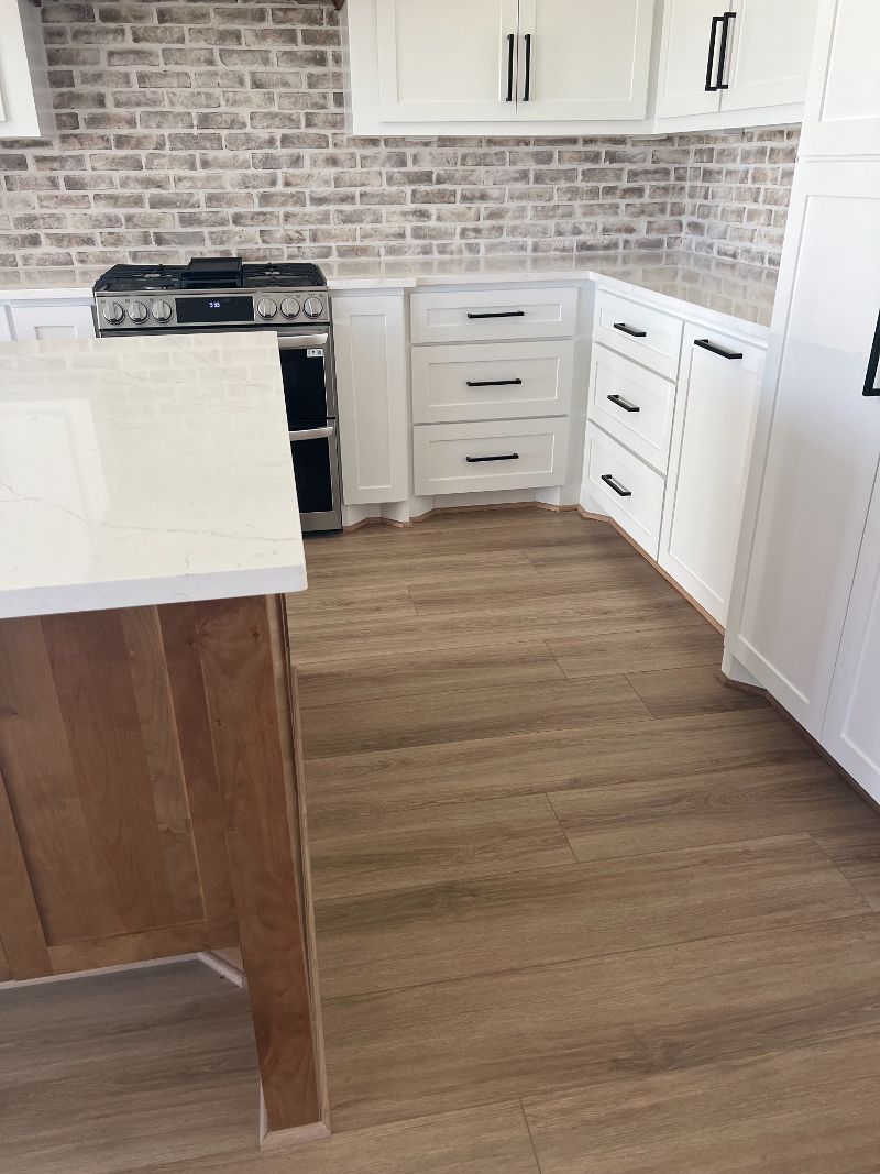 A kitchen with wooden floors , white cabinets and a stove.