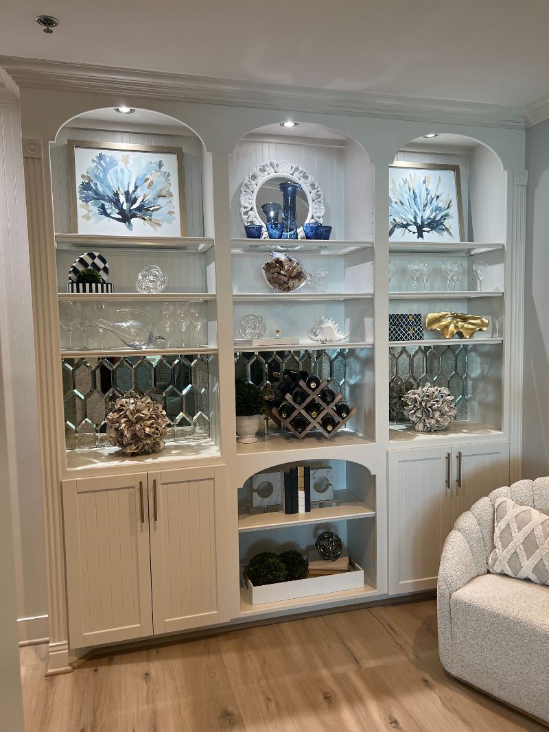 A living room with a couch , shelves , and a wine rack.
