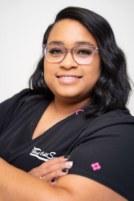 A woman wearing glasses and a black shirt is smiling for the camera.