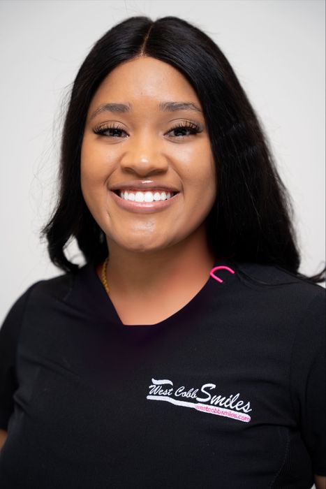 A woman wearing a black shirt with the word smiles on it is smiling for the camera.
