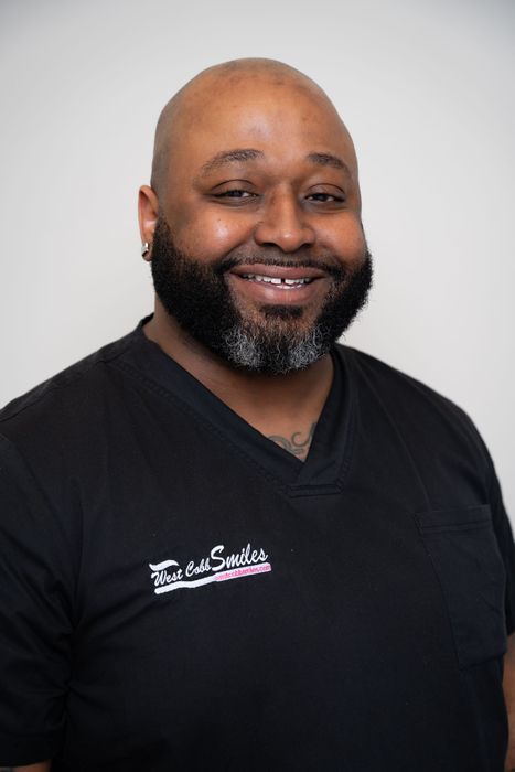 A man with a beard is wearing a black shirt and smiling.