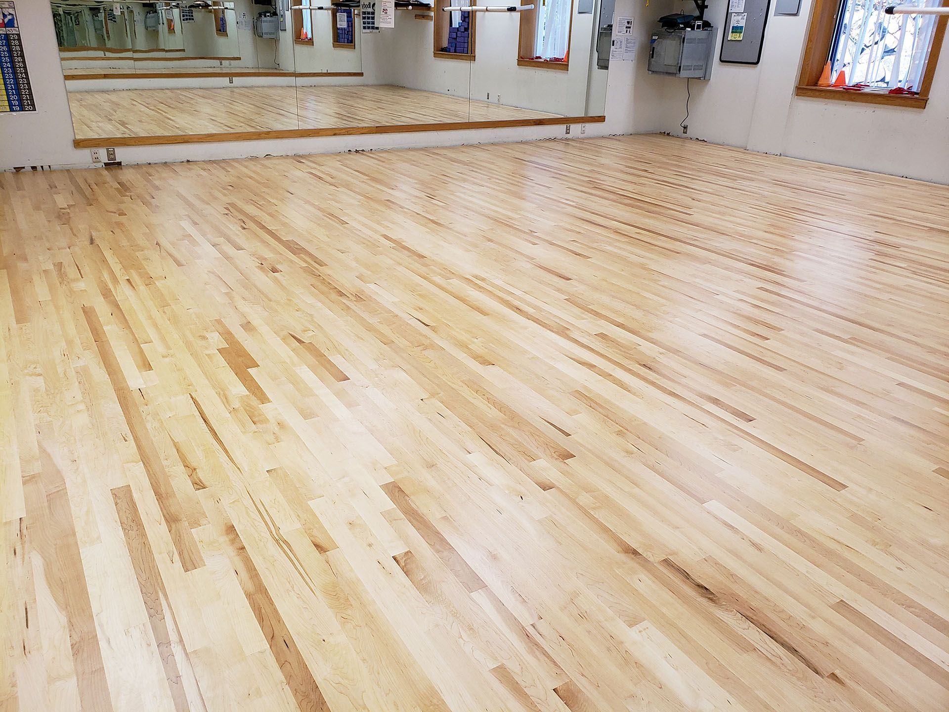 A dance studio with a wooden floor and mirrors