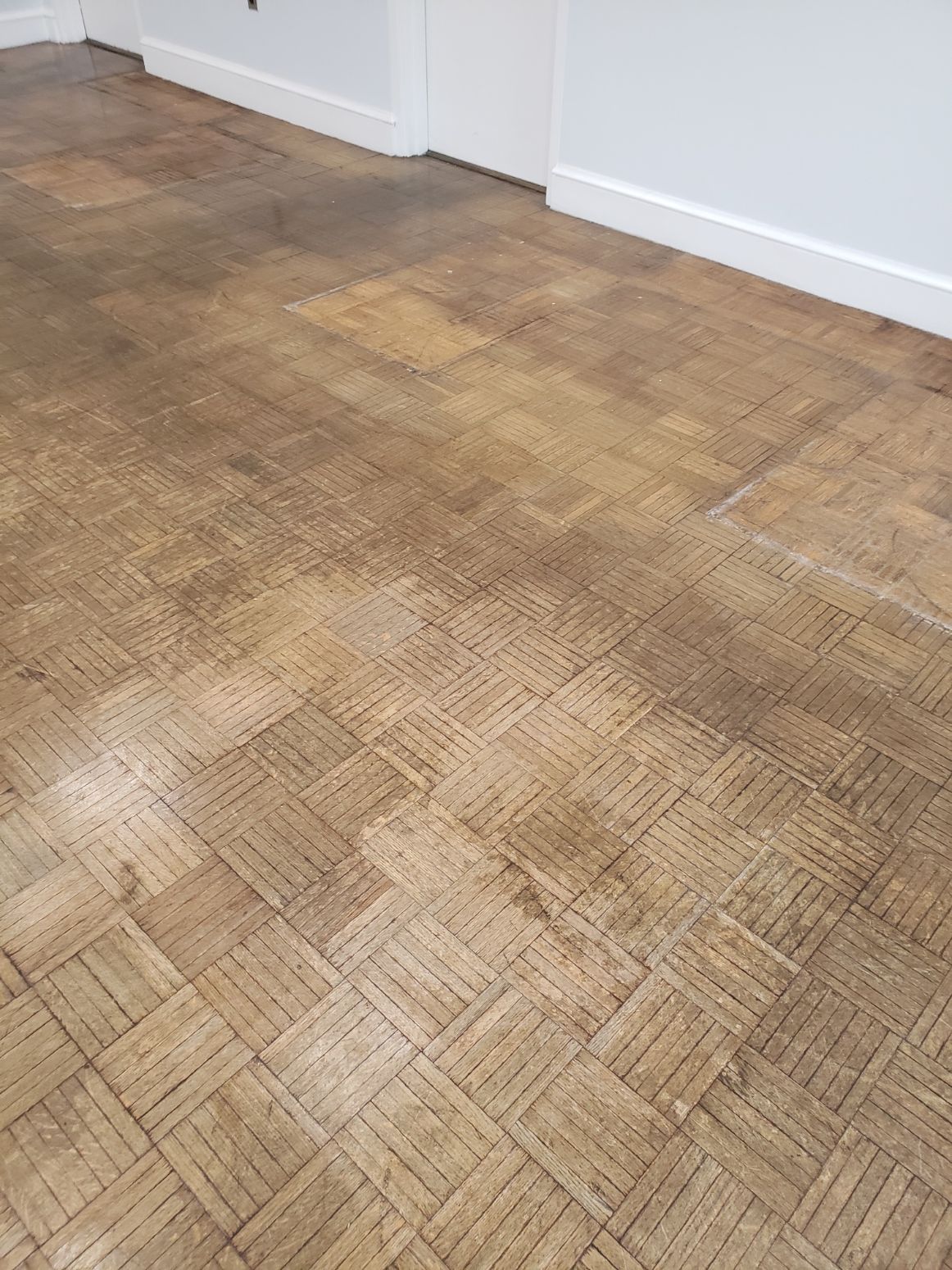 A close-up of a wooden floor in a room with white walls
