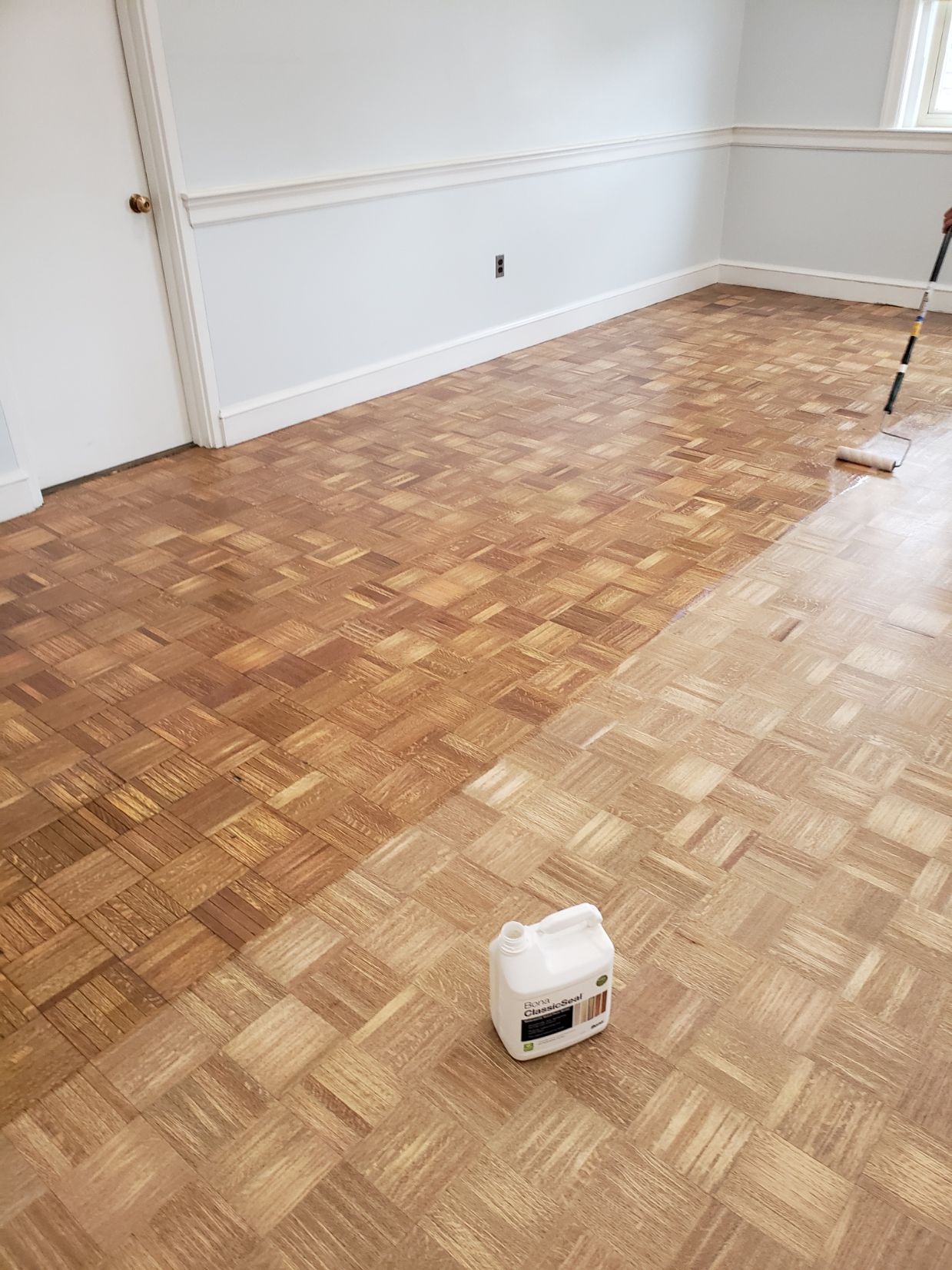 A room with a wooden floor and a bottle of paint on the floor