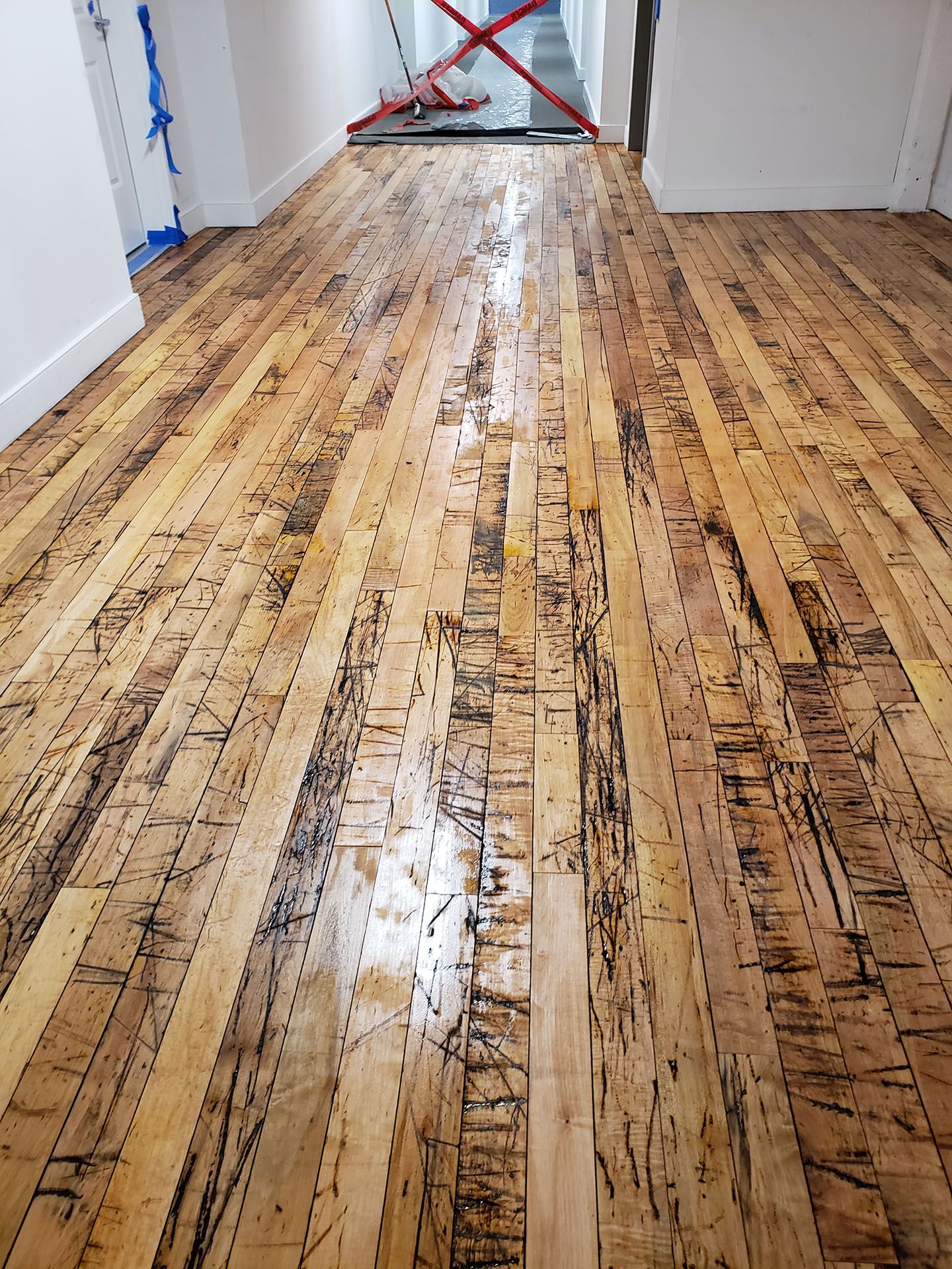 A wooden floor in a hallway with a staircase in the background