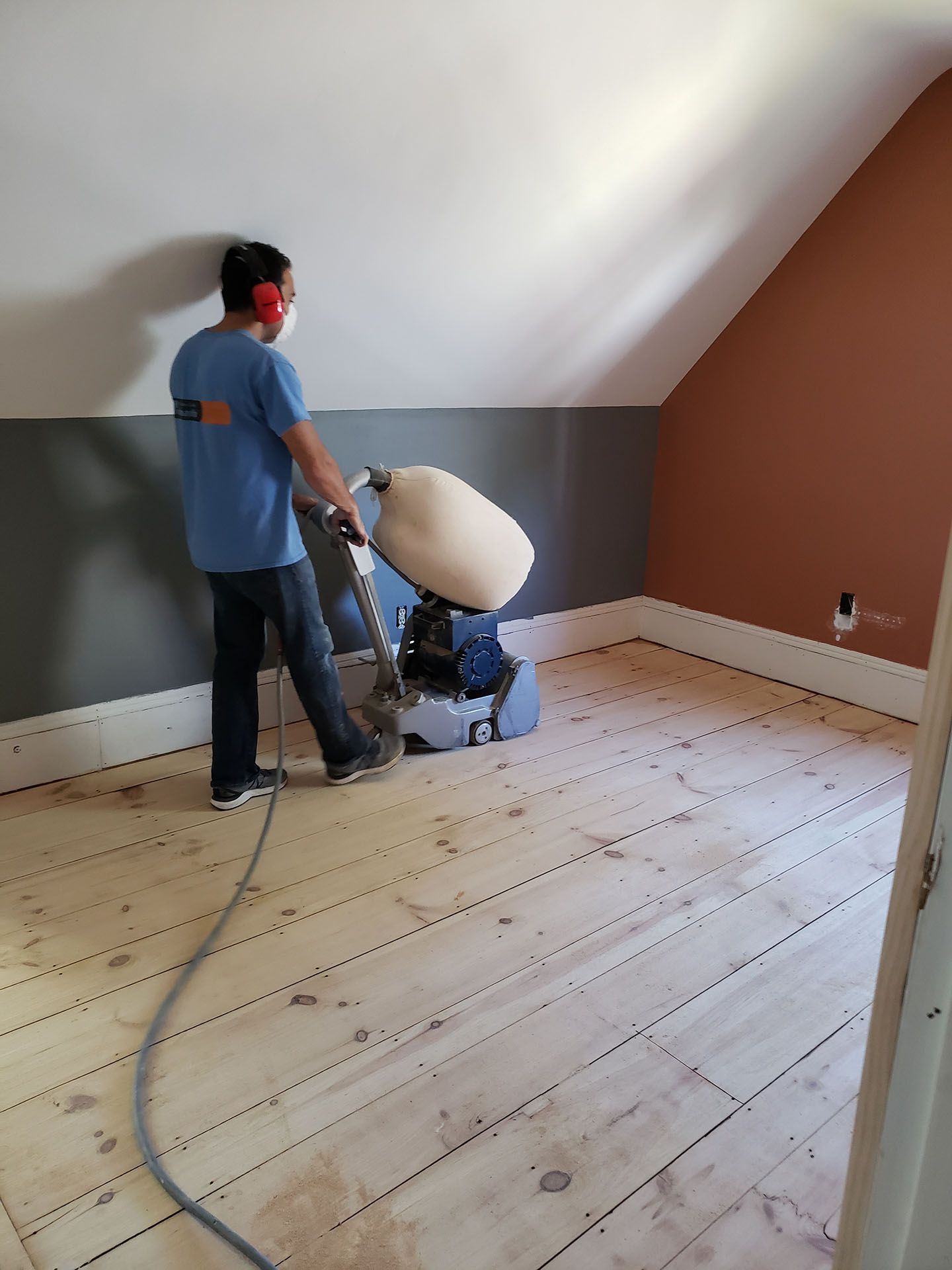 A man is sanding a wooden floor with a machine