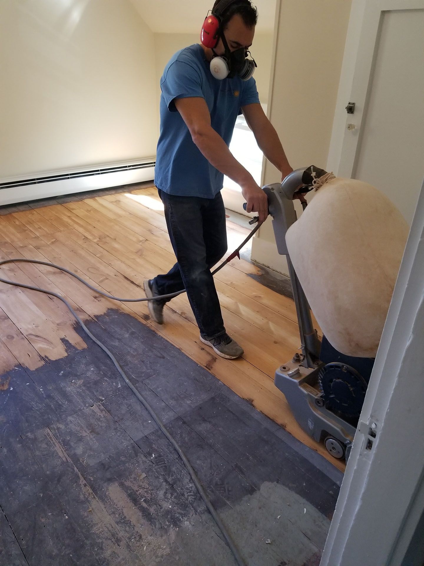 A man is sanding a wooden floor with a machine