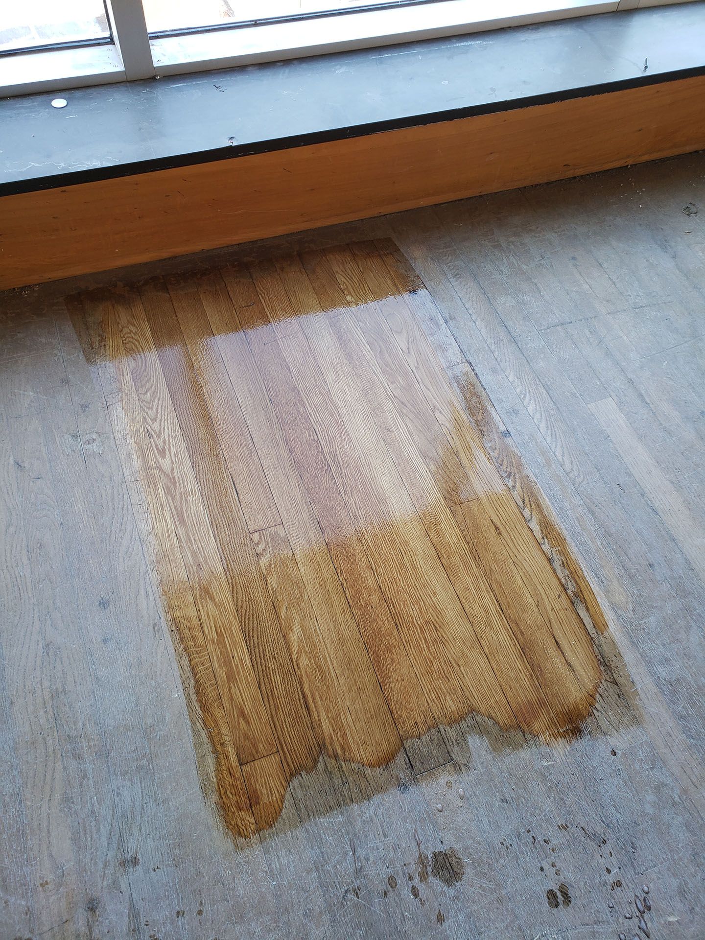 A piece of wood is sitting on the floor next to a window sill