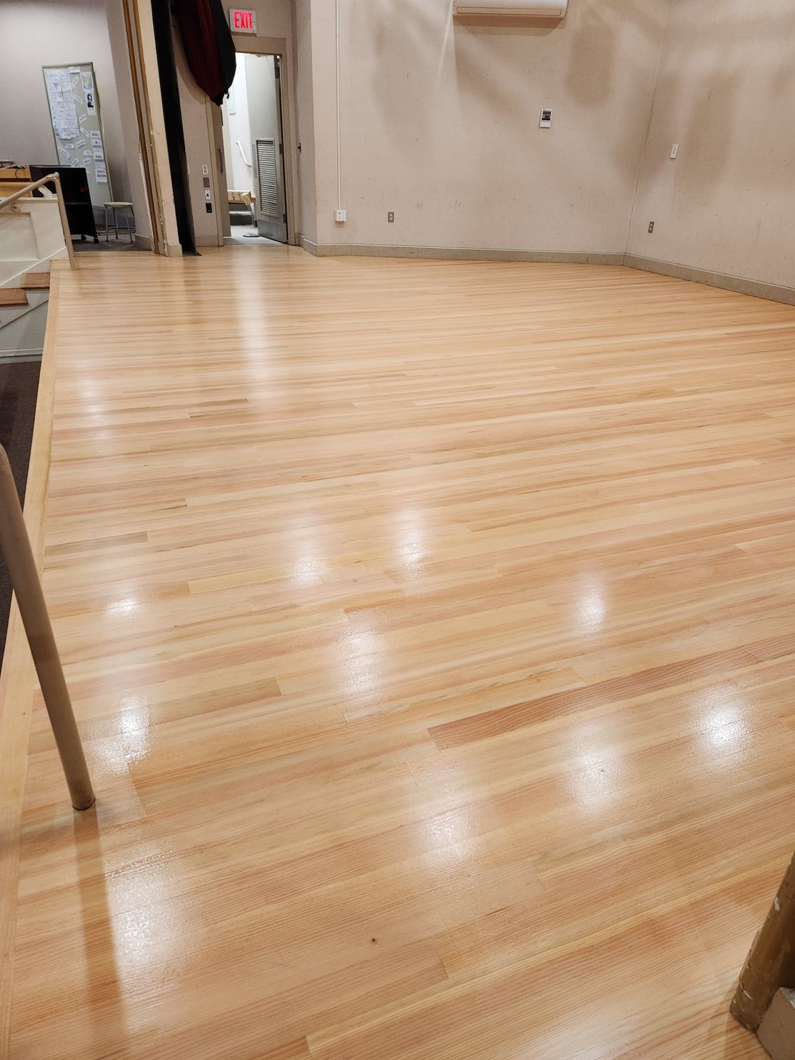 A large room with a wooden floor and a white wall