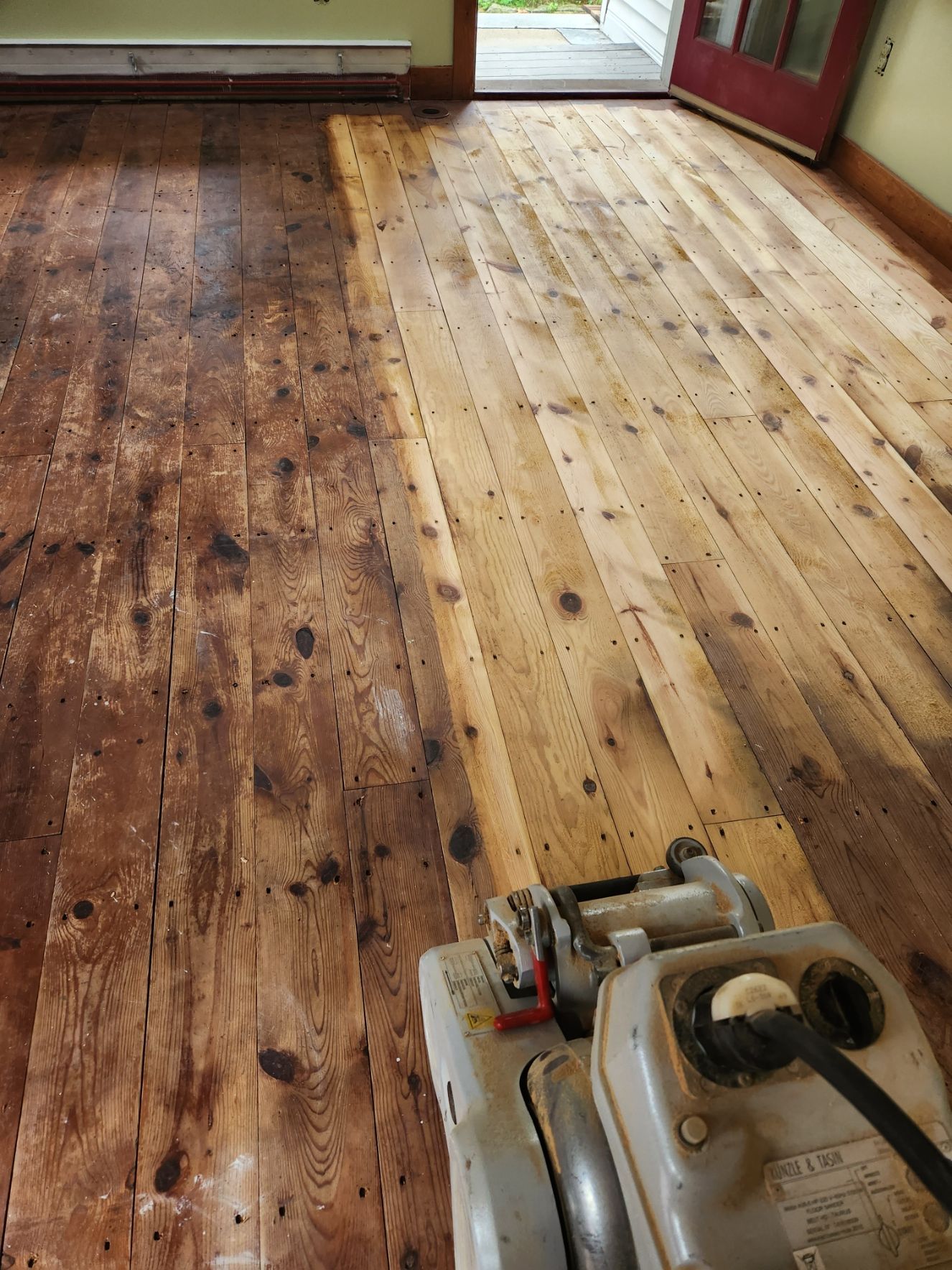 A machine is being used to sand a wooden floor