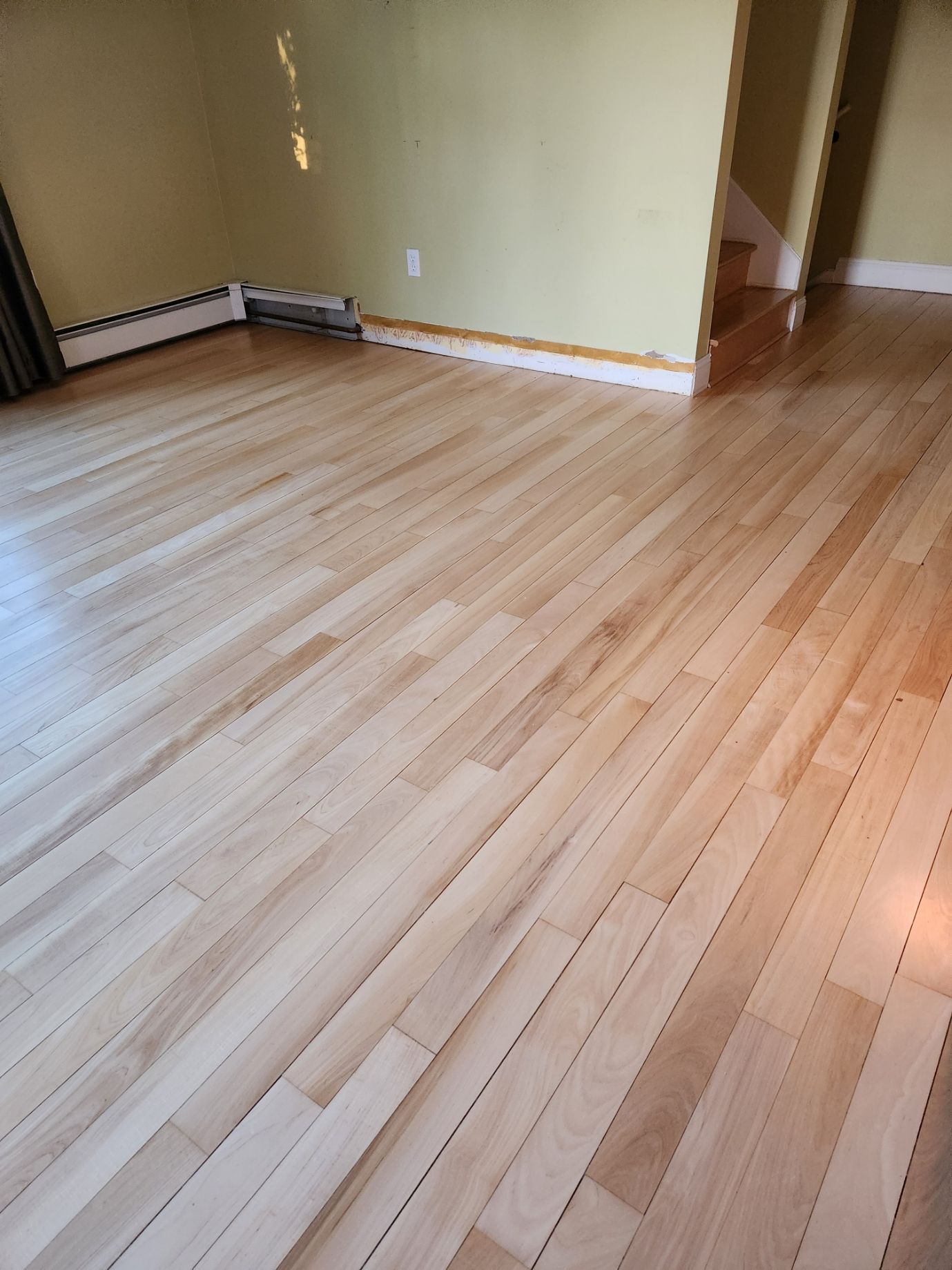 A wooden floor in a room with a yellow wall