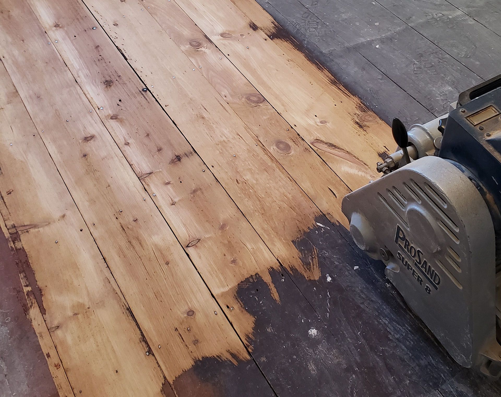 A picasso machine is being used to sand a wooden floor