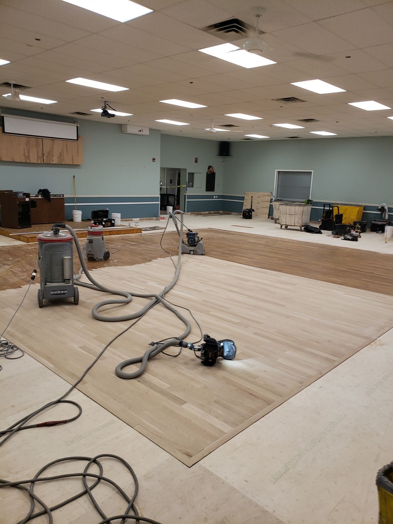 A vacuum cleaner is sitting on a wooden floor in a large room