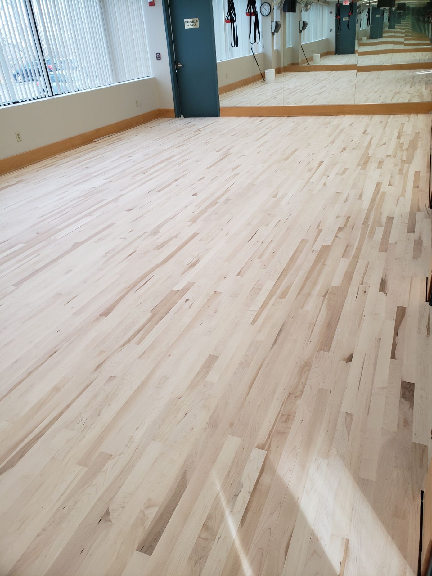 A large room with a wooden floor and mirrors