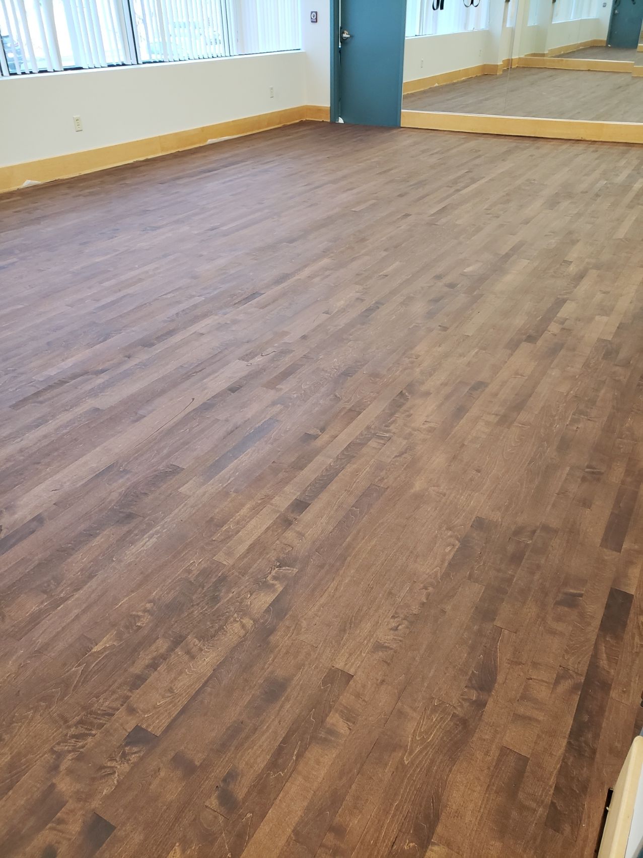 A large room with a wooden floor and a mirror