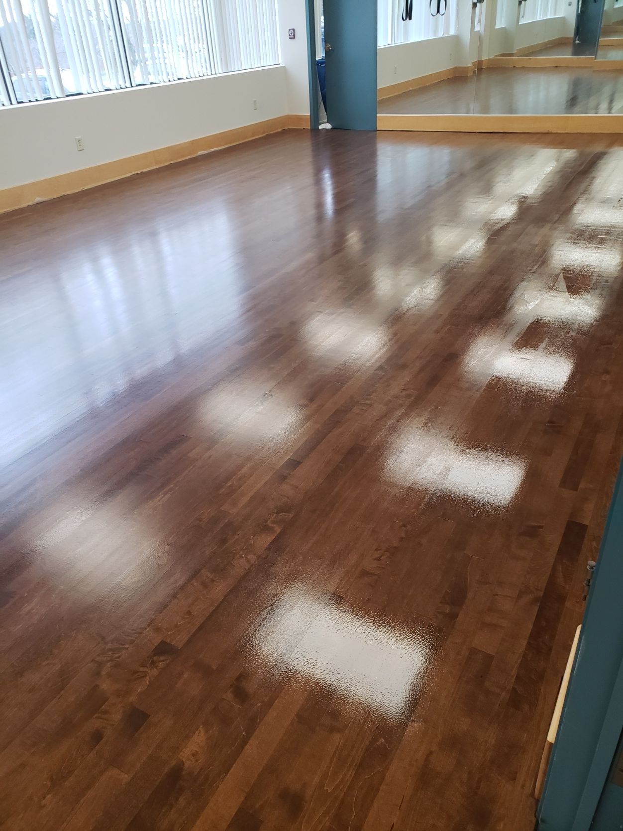 A dance studio with a wooden floor and a mirror