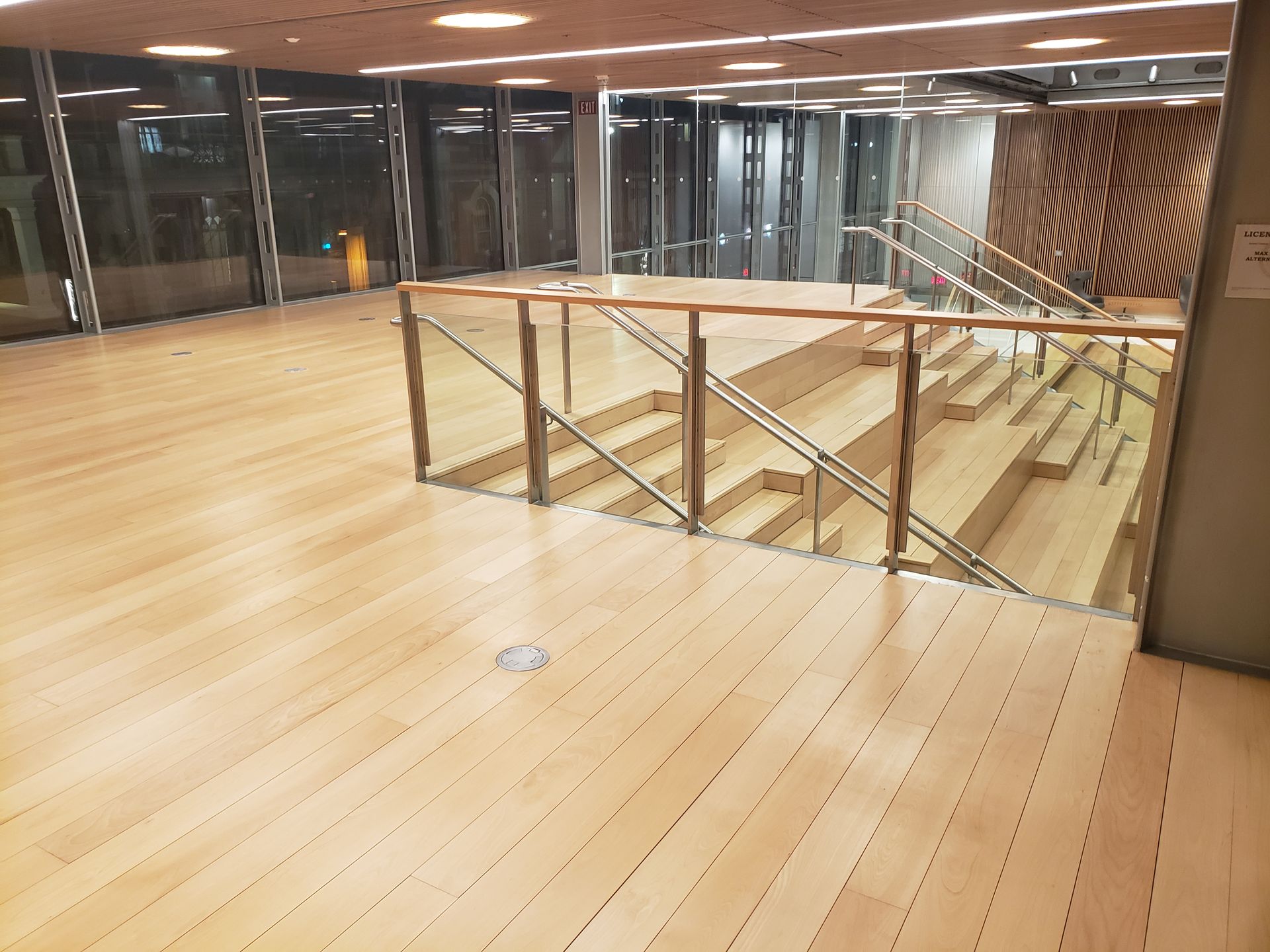 A wooden floor with stairs and a glass railing