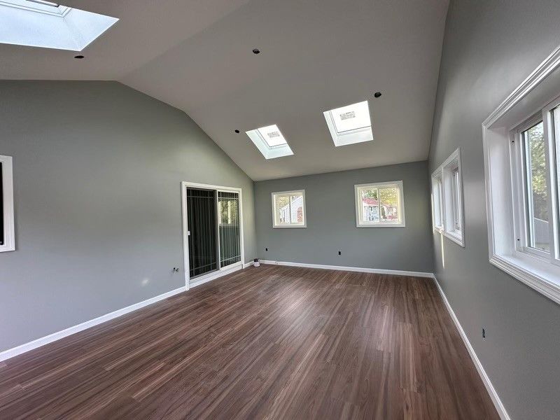 An empty living room with hardwood floors and a vaulted ceiling