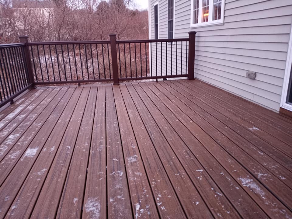 A wooden deck with a railing and a house in the background