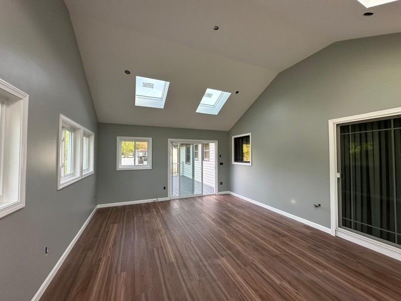 An empty room with a vaulted ceiling and skylights