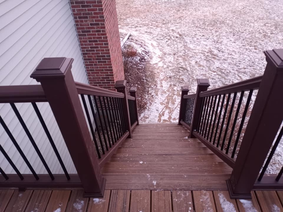 A wooden deck with stairs leading up to a brick house