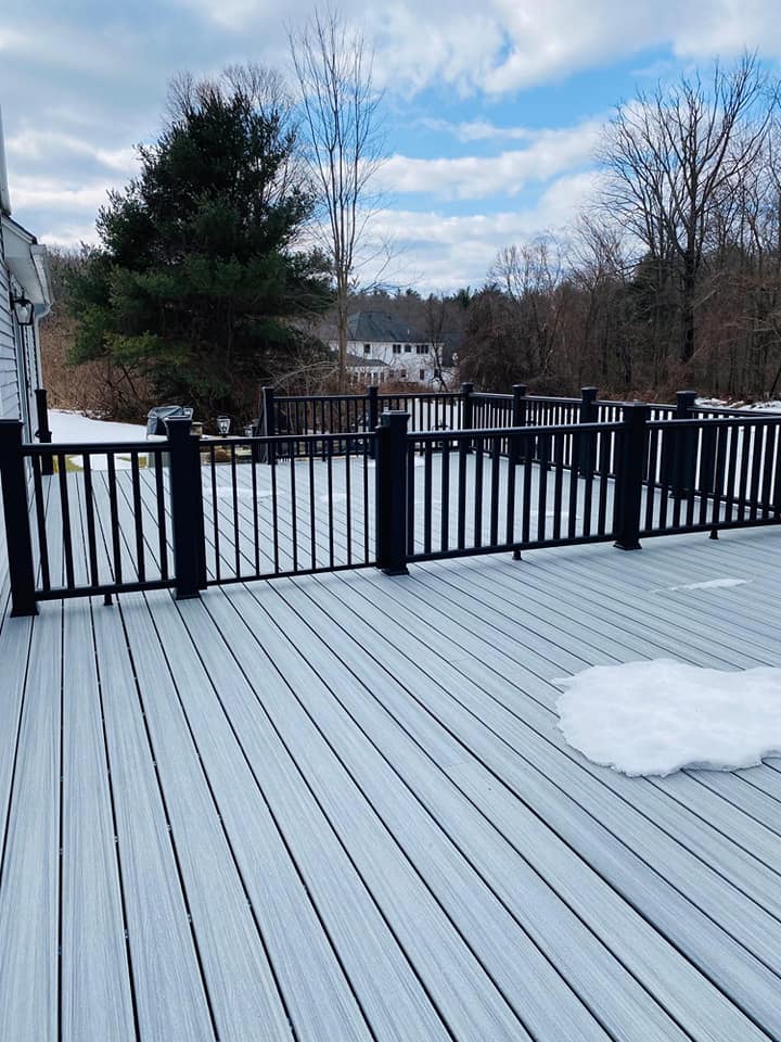 A deck with a black railing and snow on it.