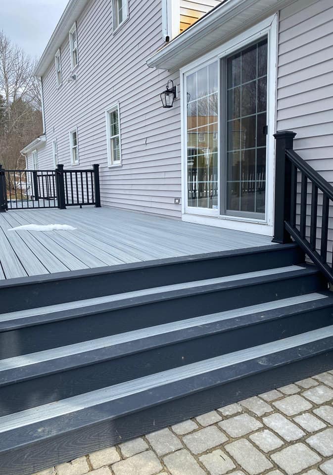 There is a deck with stairs leading up to it in front of a house.