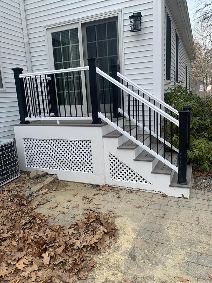 A white house with a black railing and stairs leading up to it.