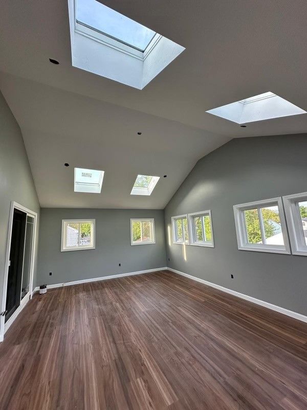A large empty room with a vaulted ceiling and skylights.
