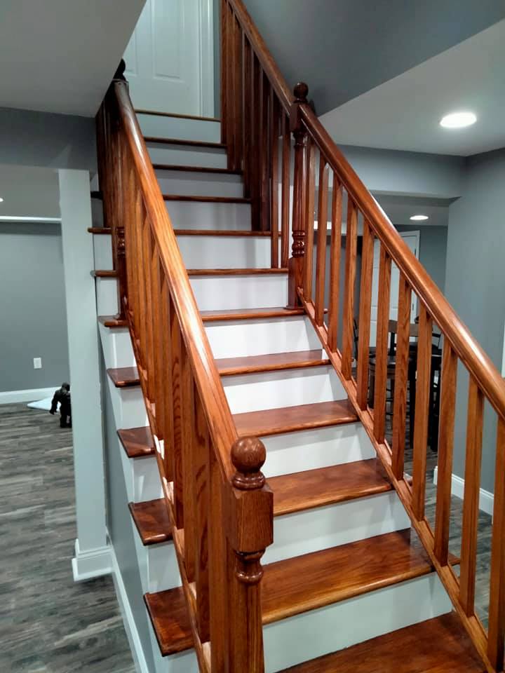 A wooden staircase with white steps and a wooden railing in a basement.