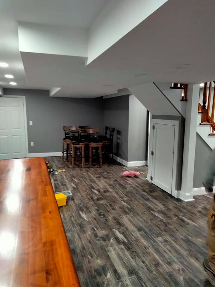 A basement with a wooden table and chairs and a staircase.