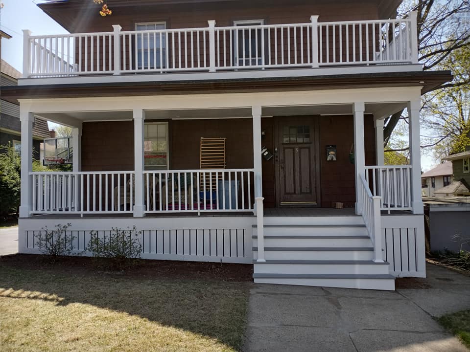 A brown house with a white porch and railing