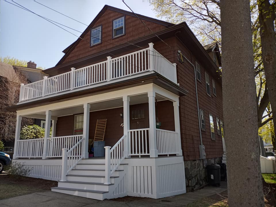A brown house with a white porch and stairs