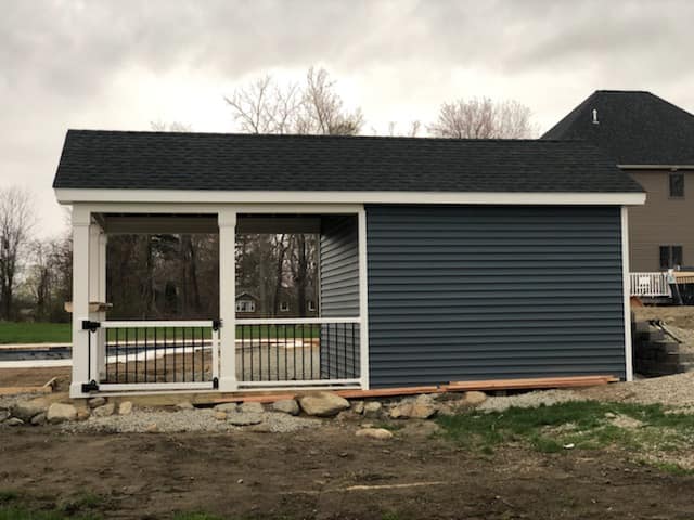 A small shed with a screened in porch and a black roof