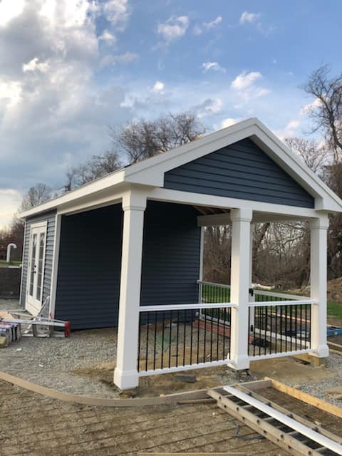 A blue house with a white porch is being built