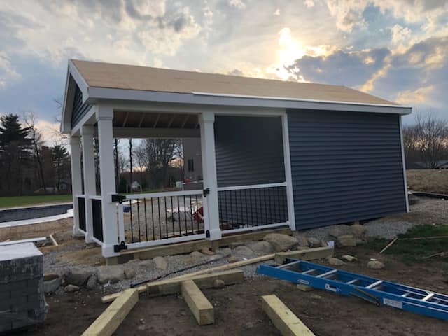 A small house with a porch and a ladder in front of it.