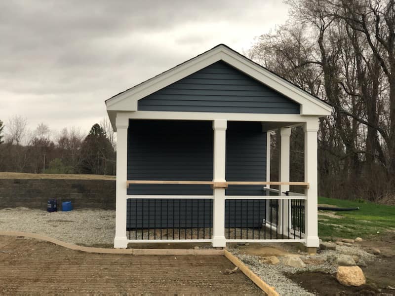 A small house with a screened in porch in the middle of a field