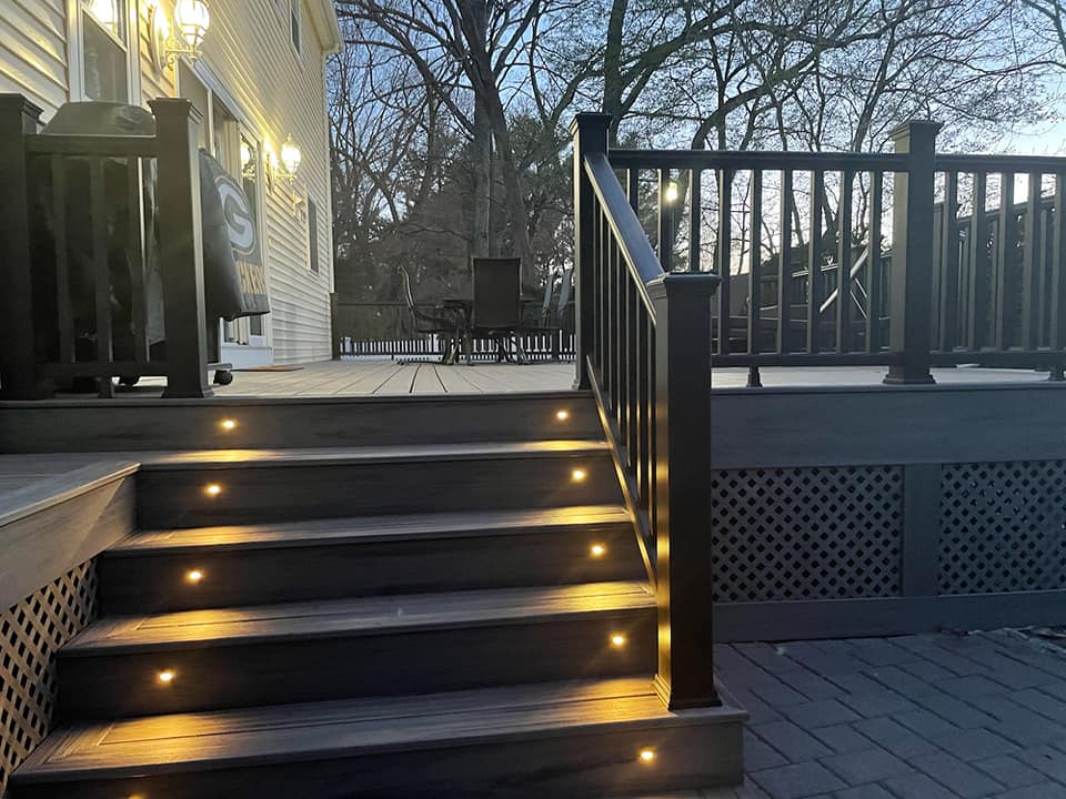 A deck with stairs leading up to it is lit up at night.
