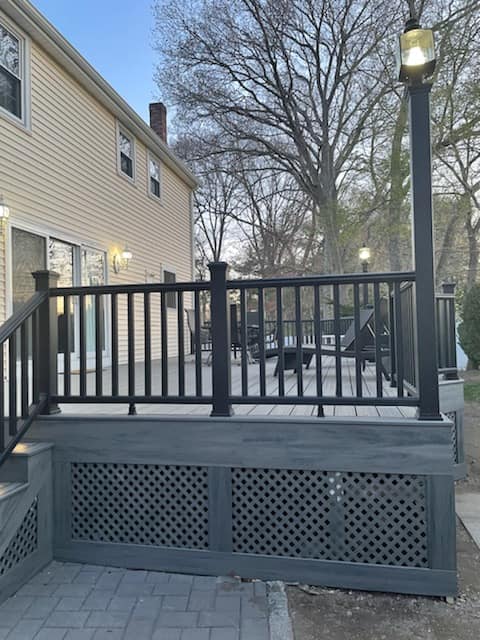 A deck with a black railing in front of a house