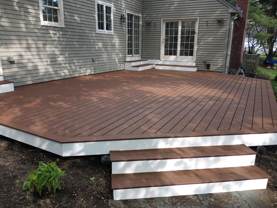 A wooden deck with white stairs in front of a house