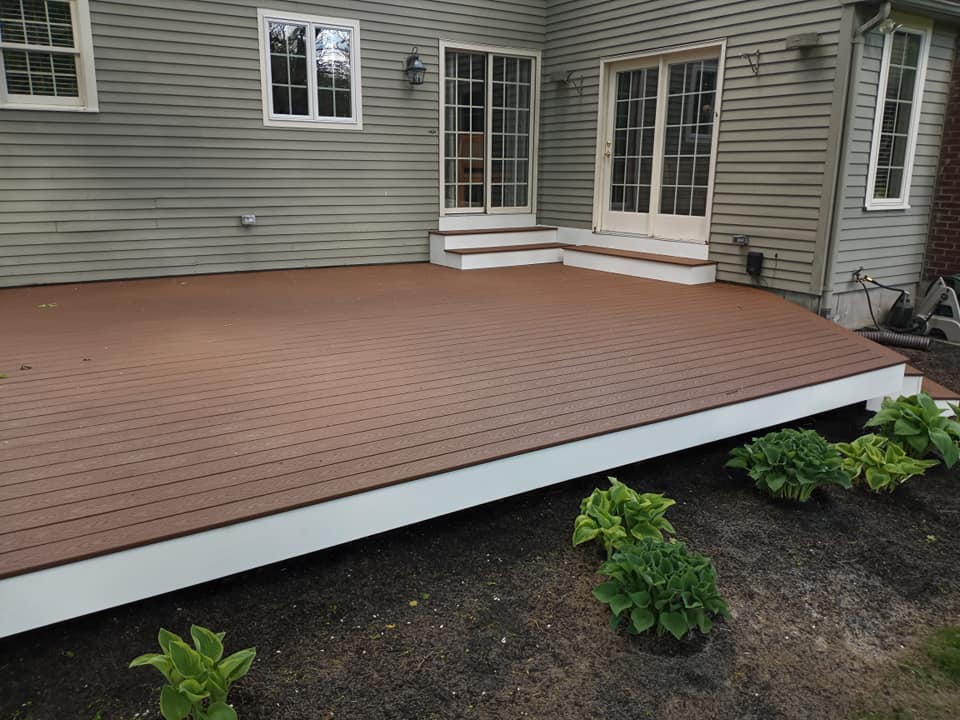 A wooden deck with stairs and a house in the background