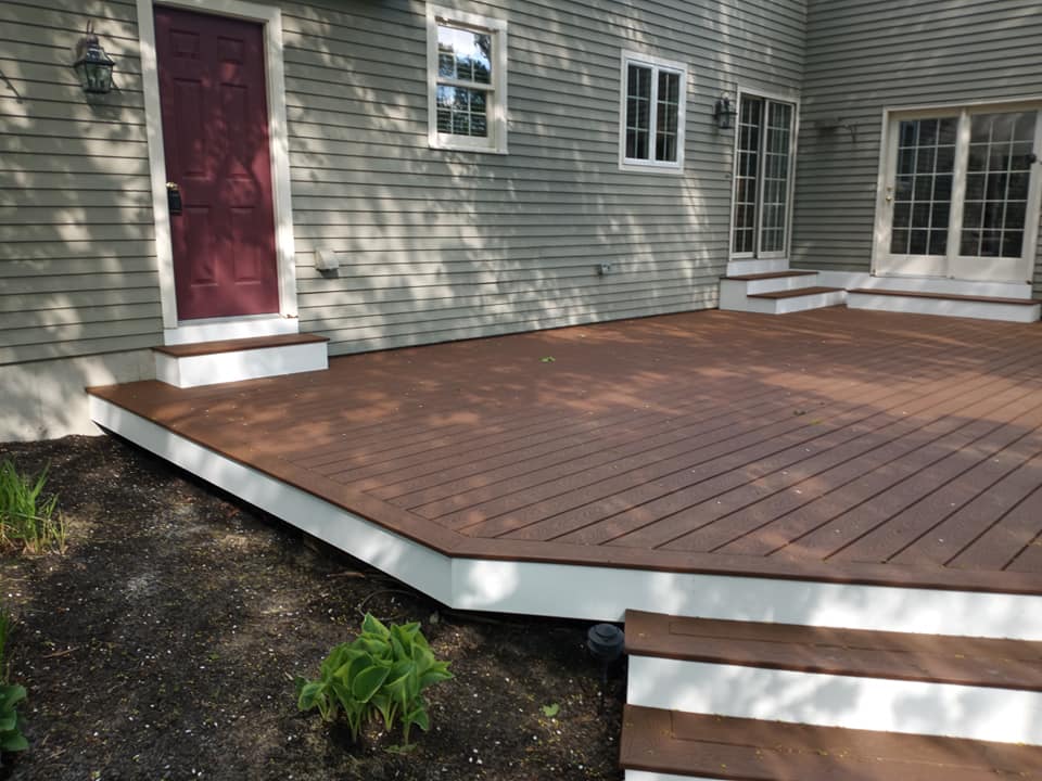 A wooden deck with stairs is in front of a house.