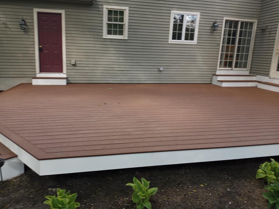 A wooden deck is in front of a house with a red door
